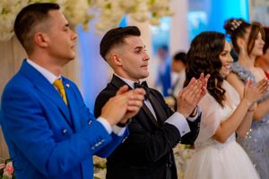 Wedding guests applauding during a celebration with blue accent lighting and floral decor.