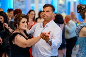 Wedding guests dancing in pairs during an elegant reception with ambient blue lighting.