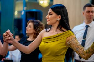 Elegant dancer in yellow one-shoulder dress with gold lace sleeve during a group dance.