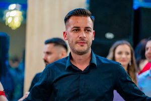 Dancer in black button-up shirt at formal indoor event with ambient lighting.