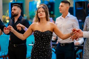 People dancing together at an elegant event with blue lighting and formal attire.