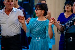 Couples dancing in a line formation at a formal social gathering with blue ambient lighting.