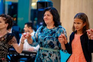 Group of people dancing in formation at a formal social gathering with teal accents.