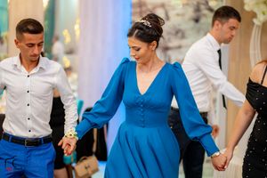 Dancers in formal attire moving together at an event with a woman in a striking blue dress.
