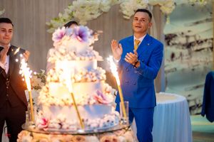 Guests in formal attire celebrating near a sparkler-lit wedding cake.