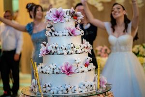 Tiered white wedding cake adorned with delicate pink and purple flowers at an elegant reception.
