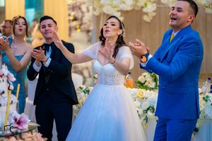 Wedding celebration with guests dancing and celebrating around an elegant floral cake.