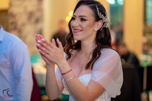 Wedding guest in white dress applauding during celebration at elegant venue.