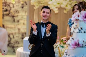 Wedding guest in formal attire clapping during reception celebration.