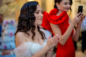 Wedding party members dancing and celebrating in a festively decorated reception hall.