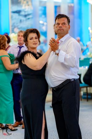 Couples dancing in formal attire under blue ambient lighting at wedding reception.
