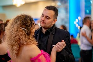 Formal wedding reception with couples dancing under vibrant blue lighting effects.