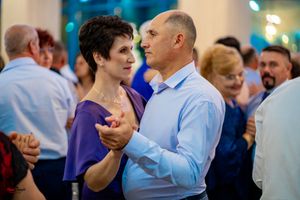 Guests dancing and socializing at an indoor wedding reception with ambient blue lighting.