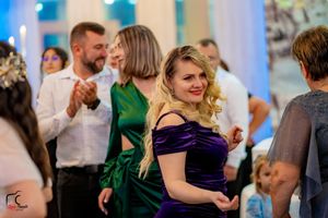 Wedding guests dancing and celebrating in formal attire under decorative lighting.