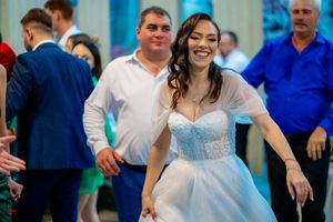 Wedding reception guests dancing and celebrating in a venue with blue accent lighting.