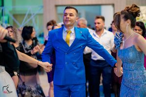 Wedding guests dancing and celebrating in a venue with colorful lighting and decorations.