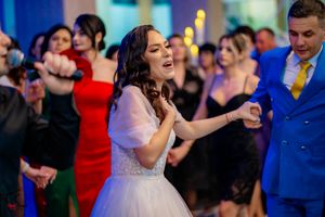 A woman in a white dress passionately dances during a celebration with blue lighting.