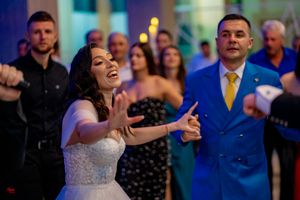 Wedding guests dance and celebrate with enthusiasm under blue ambient lighting.