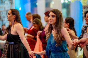 Party guests in elegant dresses dance together at a formal celebration.