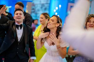 Wedding guests dance and celebrate joyfully at an elegant reception with blue lighting.