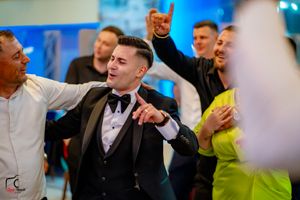 Wedding guests dancing and celebrating enthusiastically at a reception with blue lighting and festive atmosphere.