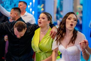 Party guests dancing energetically at an indoor celebration with bright blue ambient lighting.