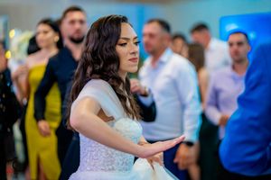 A bride in a lace dress dances expressively on the dance floor at a celebration.