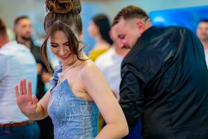 Guests dancing enthusiastically at a wedding reception with blue ambient lighting.