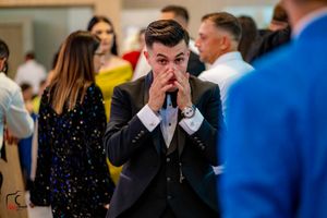 Guest in formal attire shows emotional reaction during wedding celebration.