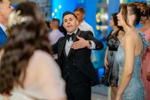 Guest in black tuxedo shows off dance moves at wedding reception.