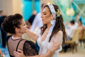 Wedding guests dance together in an elegant reception hall with turquoise lighting and decor.