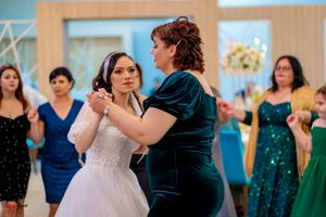 Wedding celebration showing guests dancing in pairs at an indoor venue with teal accents.