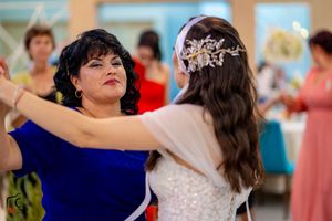 Wedding party members in vibrant dresses dance together during reception celebrations.