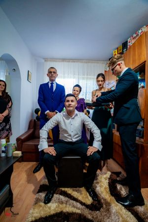 A gathering of formally dressed people in a small room with a fur rug and wooden furniture.