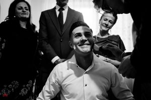 A black and white photo showing a joyful moment during formal preparations indoors.