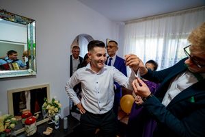 People gathered in formal wear participate in what appears to be a wedding tradition or game.