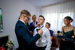 Formal event attendees participate in traditional wedding customs in an indoor setting.