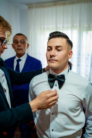 Close-up shot of someone adjusting a black bowtie on a white dress shirt.