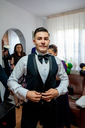 Someone wearing a black vest and white shirt prepares for a formal event.