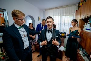 Multiple people in formal attire prepare for an event in a bright interior space.