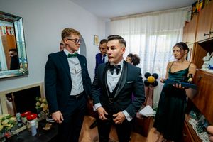 Wedding preparation scene with multiple people in formal wear getting ready.