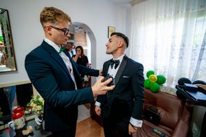 Wedding preparation scene with people in suits adjusting formal wear.