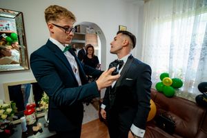 Wedding party members in formal attire getting ready in a bright room with decorations.