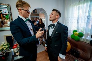 Groomsmen in dark suits preparing for wedding ceremony in living room.