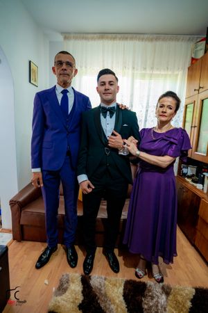 Formal family photo showing three generations in coordinated evening wear on a patterned rug.
