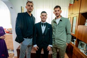 People in formal wear gather for photos in a home setting.
