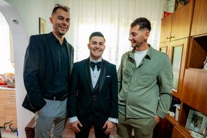 Group poses together in mixed formal attire against interior background.