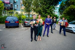 Wedding celebration with guests gathered in a parking area near residential buildings.