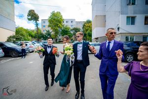 Wedding party members in formal attire playfully posing together in a parking lot.