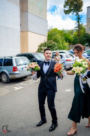 Wedding attendees in formal wear striking fun poses outside a building.